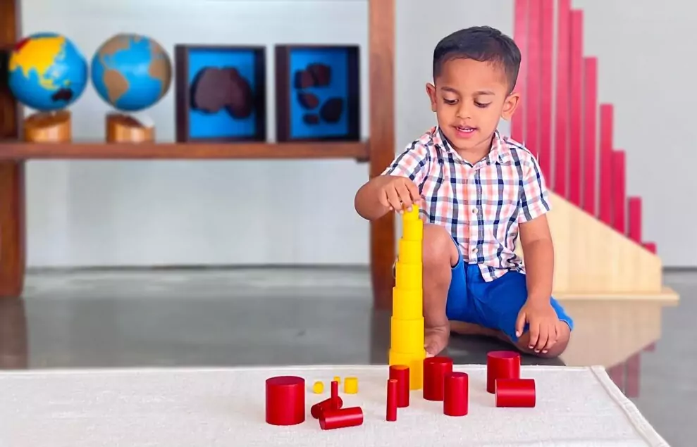 child buiding a tower using knobless cylinder 989x635 1
